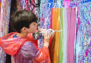 a boy squirting paint onto a canvas