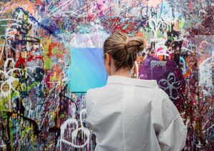 a person standing in front of a graffiti covered wall